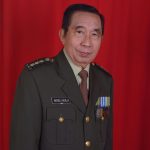 Portrait d'un officier militaire en uniforme avec des médailles sur fond rouge