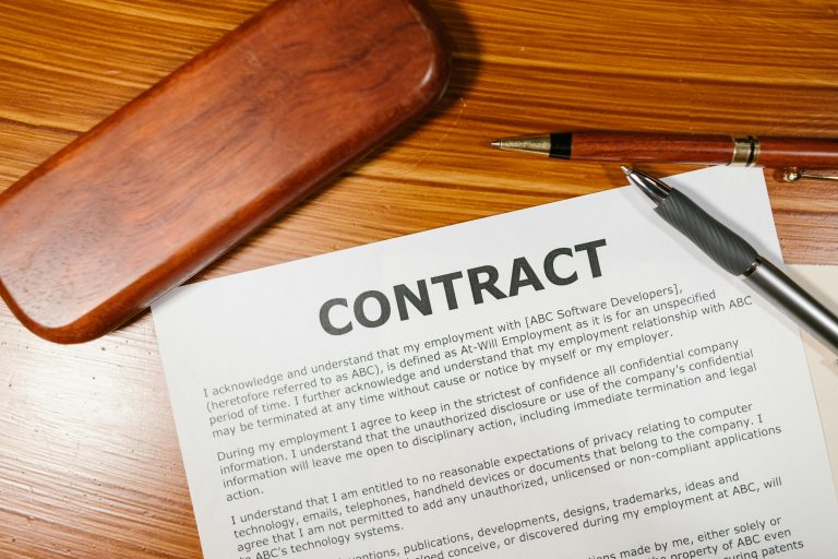 Un gros plan d'un contrat et d'un stylo sur un bureau en bois, idéal pour les thèmes professionnels.