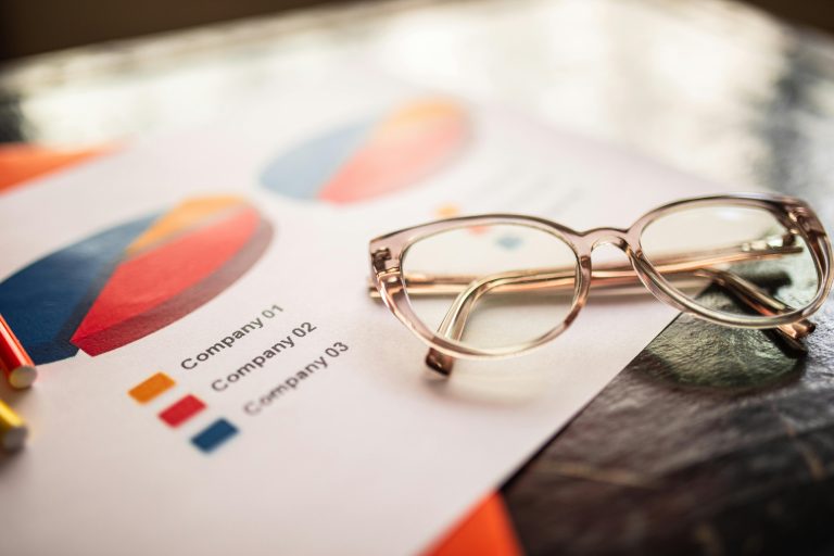 Gros plan de lunettes sur une table avec des graphiques d'affaires colorés.