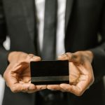 Close-up of a businessman holding a blank credit card with both hands, emphasizing finance. Gros plan d'un homme d'affaires tenant une carte de crédit vierge à deux mains, mettant l'accent sur la finance.
