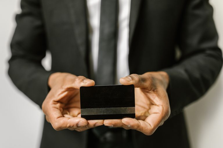 Close-up of a businessman holding a blank credit card with both hands, emphasizing finance. Gros plan d'un homme d'affaires tenant une carte de crédit vierge à deux mains, mettant l'accent sur la finance.