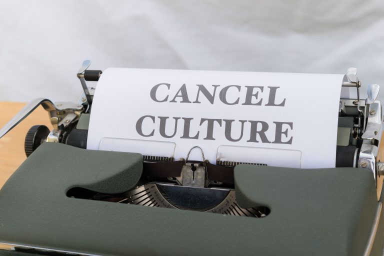 Close-up of a vintage typewriter with paper reading 'Cancel Culture', signifying social media trends. Gros plan d'une machine à écrire vintage avec du papier affichant « Cancel Culture », signifiant les tendances des médias sociaux.