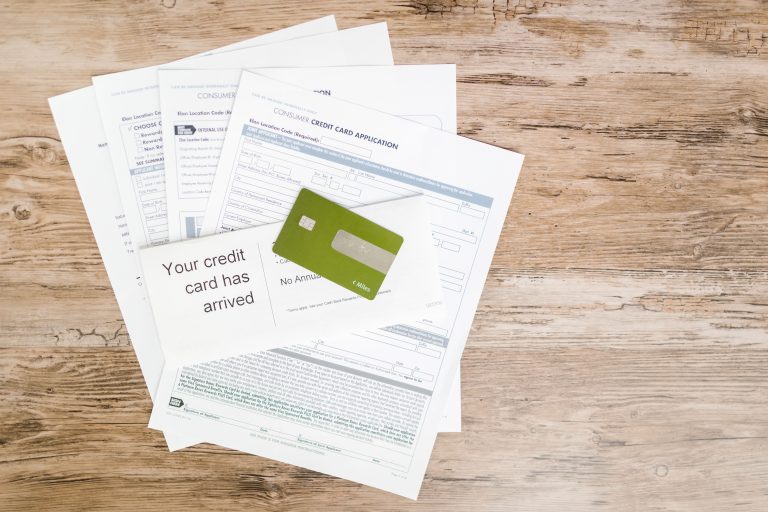 Top view of credit card and application documents on wooden surface. Vue de dessus d'une carte de crédit et de documents de demande sur une surface en bois.