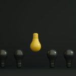 A single yellow light bulb highlighted among dark ones symbolizing creativity and innovation. Une seule ampoule jaune mise en évidence parmi des ampoules sombres symbolisant la créativité et l'innovation.