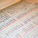 Close-up of a vintage handwritten ledger detailing financial records and accounts. Gros plan sur un grand livre manuscrit vintage détaillant les dossiers et comptes financiers.