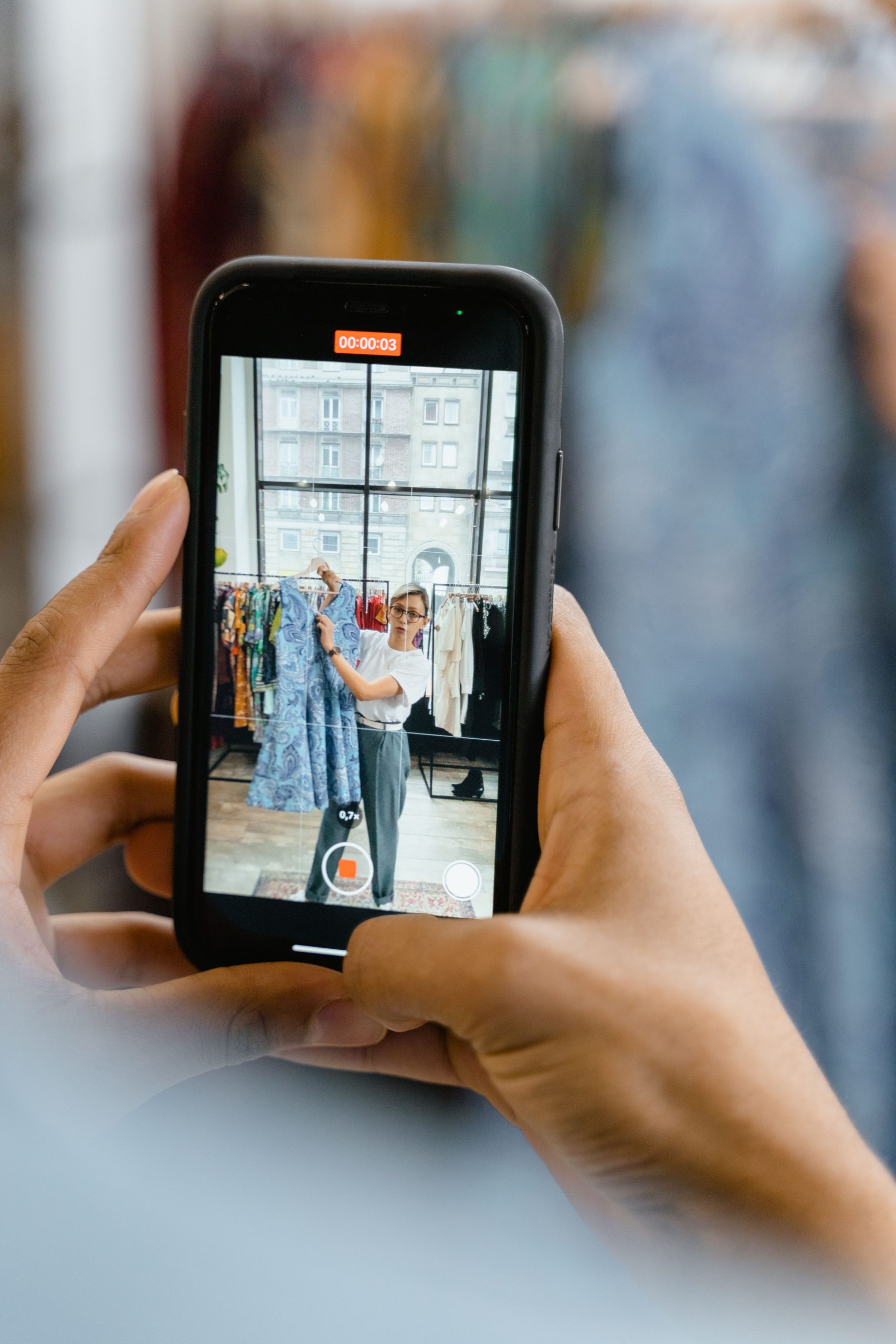 Woman recording video of a blue dress for online fashion business in airy studio. Femme enregistrant une vidéo d'une robe bleue pour une entreprise de mode en ligne dans un studio aéré.